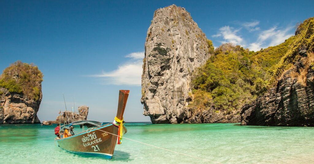 A picturesque tropical beach with a traditional boat and stunning limestone cliffs in clear turquoise waters.