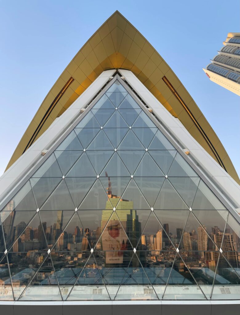 Striking glass facade reflecting cityscape in Bangkok, Thailand during daytime.